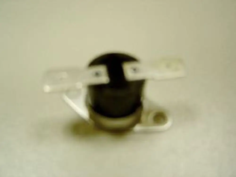 Thermostat von Remeha mit runder schwarzer Kunststoffkappe und zwei Anschlussplatten. Das Gerät sitzt auf einer Metallbasis.